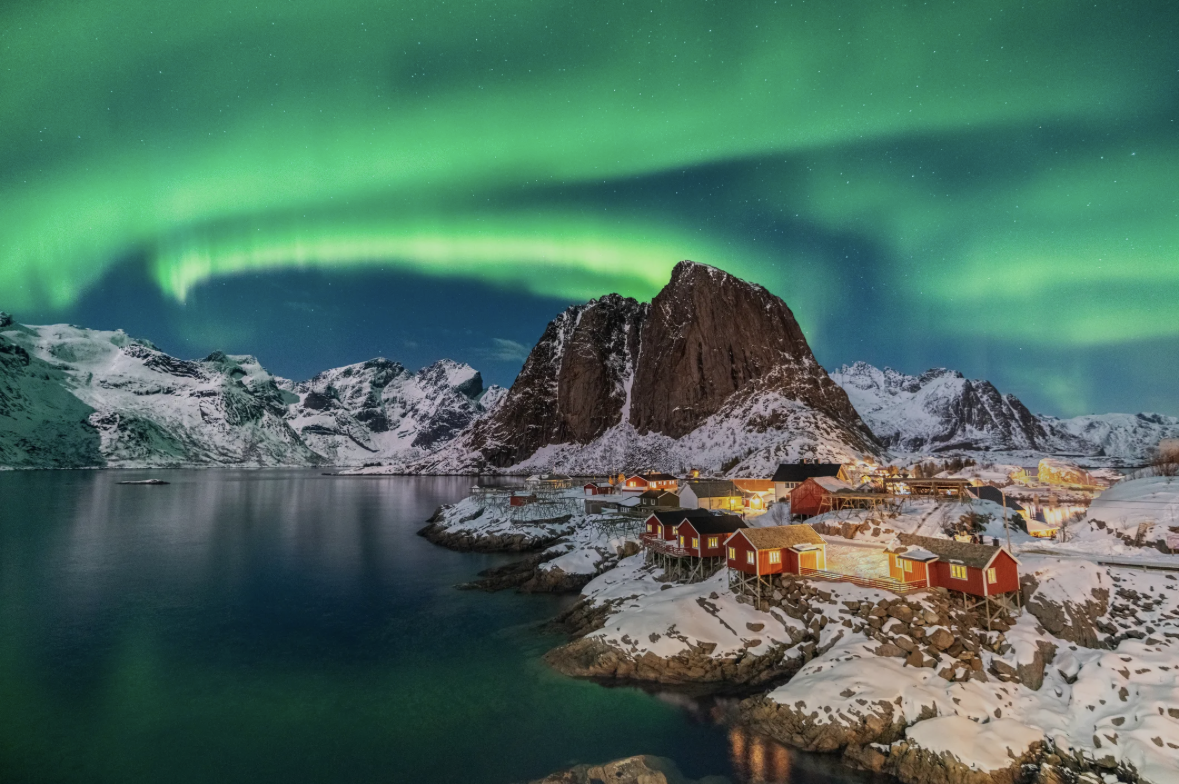 Aurora borealis over a snow-covered fishing village on a fjord