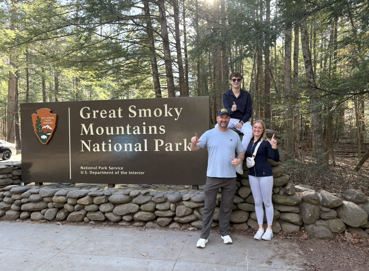 Group posing in front of the Great Smoky Mountains National Park sign, surrounded by dense forest