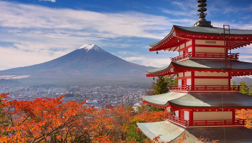 The red Chureito Pagoda framed by autumn leaves with Mount Fuji rising behind it