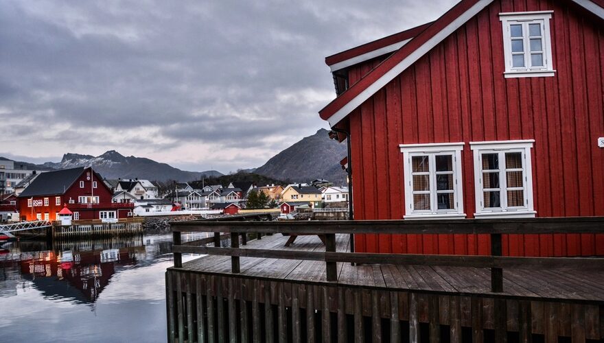 Red timber fishing cabins on the water's edge of a Lofoten fjord village in Norway