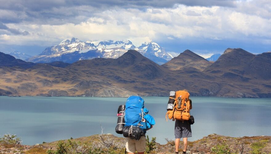 Two backpackers looking out over a glacial lake toward the peaks of Torres del Paine in Patagonia